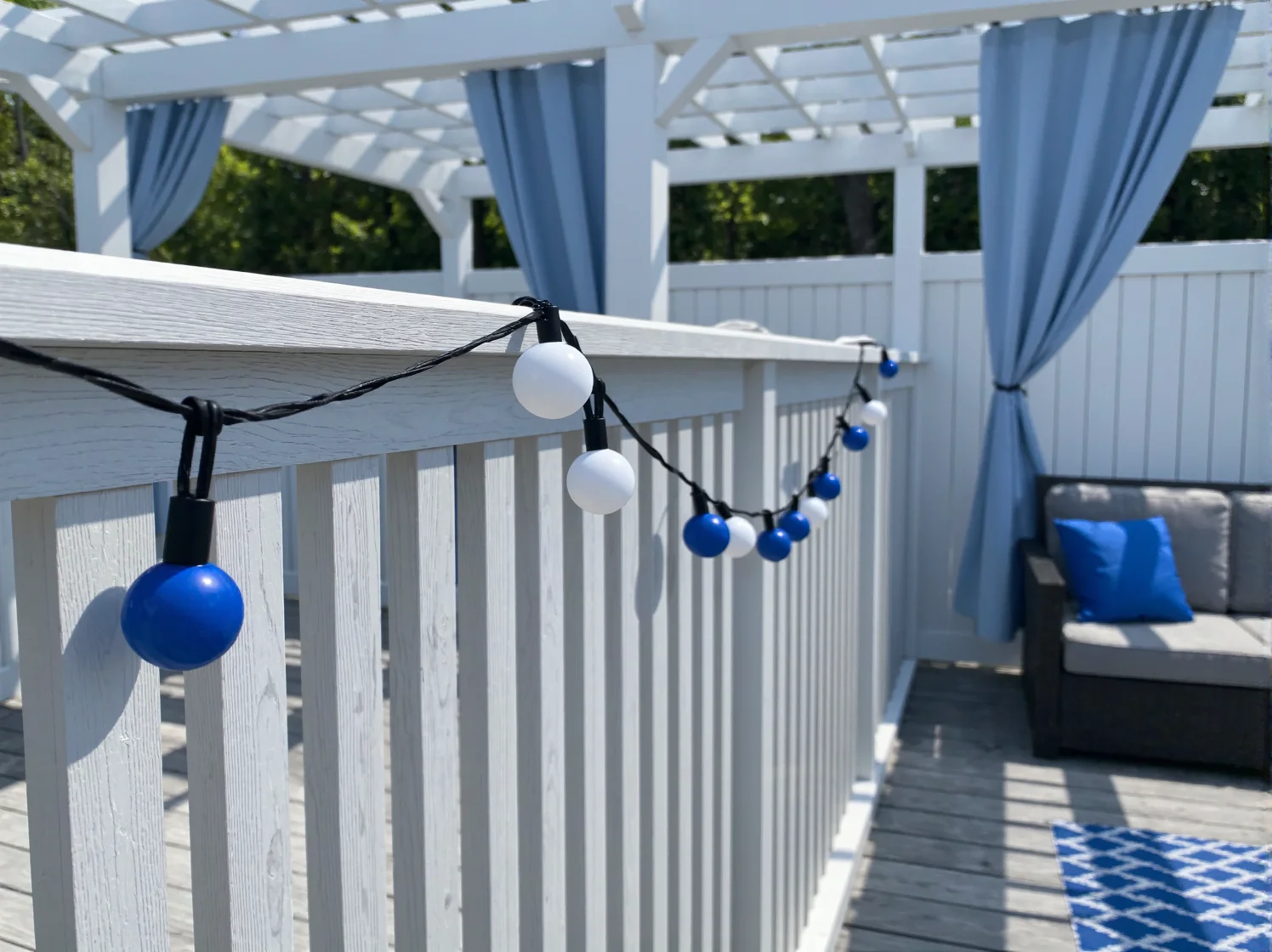 Wieczorna strefa relaksu na tarasie: styl skandynawski, błękitne LEDy i białe tekstylia ogrodowe.